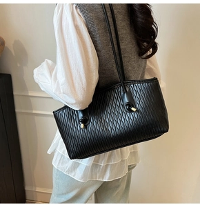 Vue détaillée du sac cabas noir en cuir plissé avec des finitions métalliques dorées