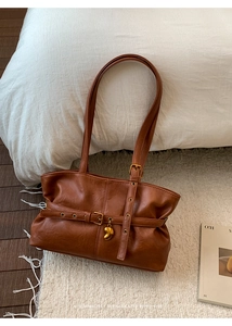 Dettaglio della borsa tote retrò marrone con cinturini incrociati e ciondolo a cuore