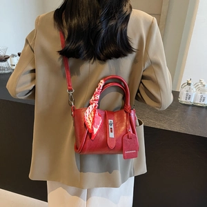 Detail of red leather bucket bag with silk scarf handle and elegant metal buckle closure