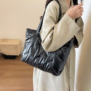 Detailed view of the black quilted tote bag with soft down texture and woven design