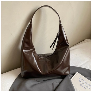 Detail of glossy dark brown synthetic leather hobo bag with sleek vertical stitching details