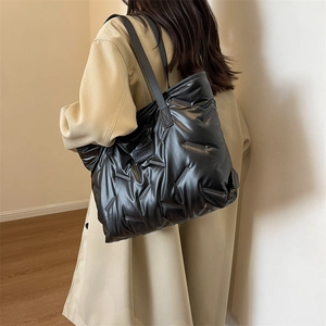 Detail view of the black puffer tote bag showing quilted texture and fashion logo label