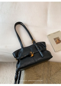 Vista dettagliata della borsa tote vintage nera in pelle con ciondolo a cuore dorato su tessuto