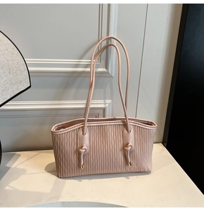 Détail du sac cabas rose avec texture plissée ondulée et boucle à nœud en métal doré