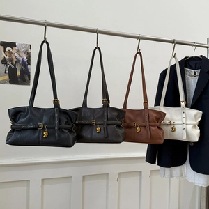 Borse tote minimaliste in nero, caffè, caramello e crema esposte su un appendiabiti
