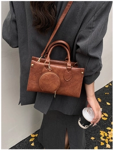 Rear view of model holding retro brown crossbody bag with matching round coin purse detail