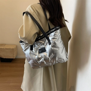 Detailed view of a silver padded tote bag with black leather straps on a trench coat