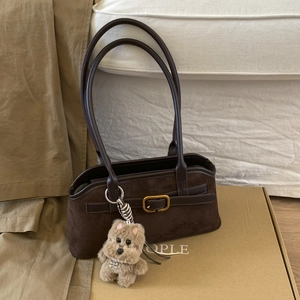 Dettaglio borsa baguette in camoscio marrone con fibbia e ciondolo a forma di cucciolo