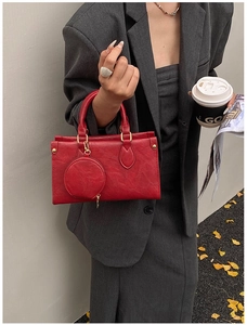 Detail of red textured leather handbag with mini round pouch and gold hardware