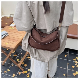 Deep brown suede shoulder bag detail showing smooth leather trim and golden hardware buckle