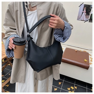 Détail du sac demi-lune en cuir noir mat avec large bandoulière et décor de feuilles