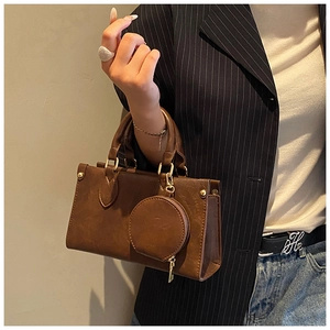 Close-up of brown vintage handbag with round handle and detachable coin purse on a model