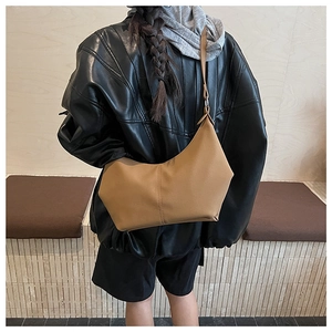 Vue détaillée d'un sac hobo minimaliste en cuir camel porté avec une veste en cuir noir