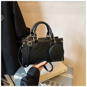 Detail of a black faux leather handbag with circular coin purse and golden hardware