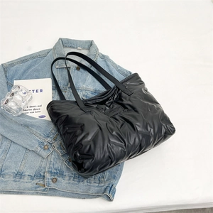 Macro detail of black quilted puffer tote bag with fashion label on soft nylon fabric