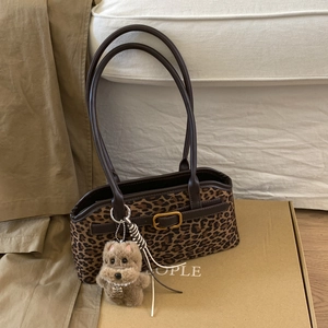Dettaglio borsa leopardata a spalla con fibbia dorata e ciondolo a forma di cane