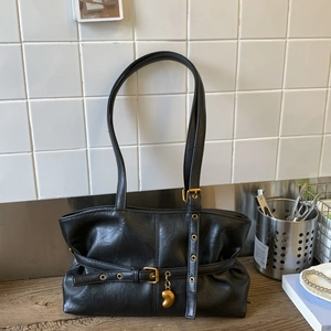 Dettaglio della borsa a spalla in pelle PU nera con ciondolo a cuore dorato e fibbie in metallo