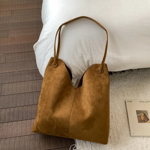 Détail du sac cabas en daim marron avec ouverture en V et fines bandoulières minimalistes