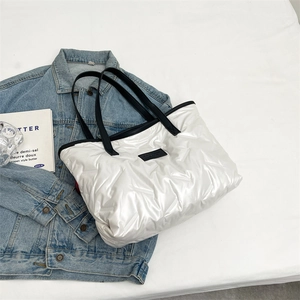 Detail of white quilted tote bag with V-pattern stitching and fashion label logo