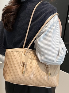 Sac cabas chic abricot à motif gaufré avec bandoulière à nœud porté par un mannequin