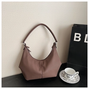 Détail du sac hobo en cuir marron foncé avec texture grainée fine et anneaux métalliques argentés