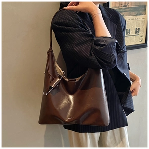 Detail of vintage brown oil wax hobo bag featuring silver pin hardware and smooth finish