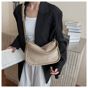 Detail of light brown faux suede half-moon crossbody bag with golden metal buckles
