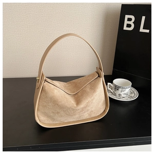 Detail of beige faux suede hobo bag featuring smooth leather trim and golden metal buckles