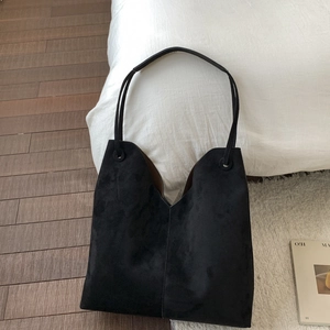 Détail du sac cabas en daim noir mat avec coupe en V élégante et fines anses d'épaule