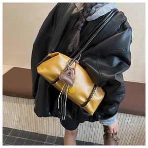 Detail of yellow leather pillow bag with smiley pendant on black shoulder strap