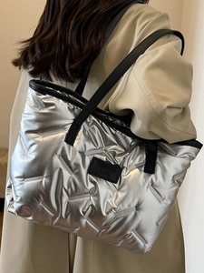 Silver quilted puffer tote bag with black straps shown on model for a stylish look