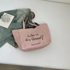 Rosa Canvas-Einkaufstasche mit kariertem Futter und Schriftzug neben Modezeitschriften