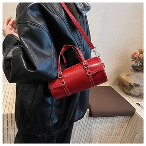 Detail shot of a red patent leather bowling bag with silver buckles on a black jacket