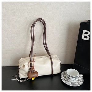 Detailed macro view of the beige barrel-shaped pillow bag with dark brown shoulder strap