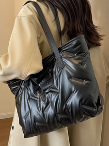 Fashionable black puffer tote bag with glossy quilted texture and shoulder straps