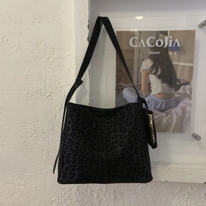 Detail of leopard print suede bucket bag showing textured fabric and small zipper pouch
