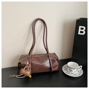 Detailed shot of dark brown Boston bag with smooth leather texture and small charm