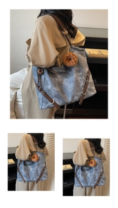 Detail of a vintage blue canvas tote with brown leather strap and a plush donut charm