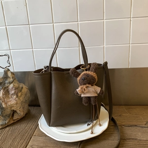 Detail of dark brown lychee grain leather crossbody bag with a cute plush bear pendant