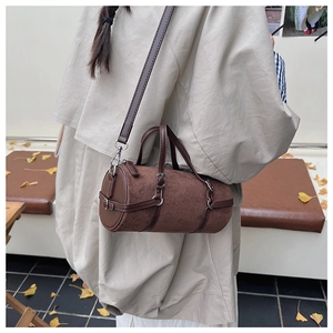 Brown suede bowling bag with leather trim carried by a model in autumn street setting