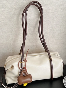 Chic cream leather cylinder shoulder bag with dark brown straps and mini bag charm