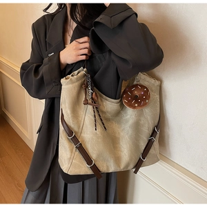 Detail of vintage tote bag in khaki canvas with plush donut charm and metal hardware
