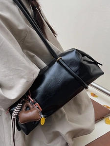 Chic black glossy shoulder bag with playful charms and slim strap for autumn fashion