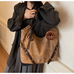 Detail view of caramel brown tote bag showing matte texture and doughnut charm accessory