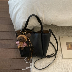 Minimalist black lychee pattern leather bucket bag with a cute brown plush bear pendant