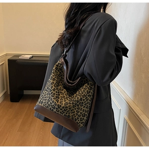Detail of the leopard print canvas bucket bag with brown leather base on a model shoulder