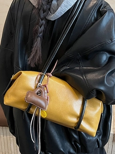 Fashionable ginger yellow faux leather shoulder bag with decorative charms and black straps
