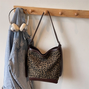 Detail of leopard print canvas bucket bag with brown leather straps and silver headphones