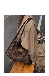 Fashionable leopard print tote bag with brown leather label shown in outdoor street style