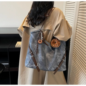 Detail of vintage grey-blue canvas tote with brown leather strap and donut charm